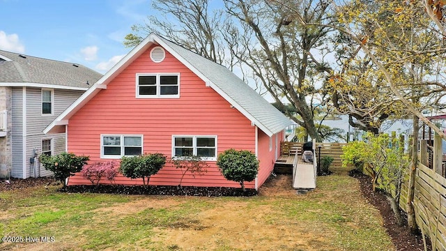 rear view of house with fence and a lawn