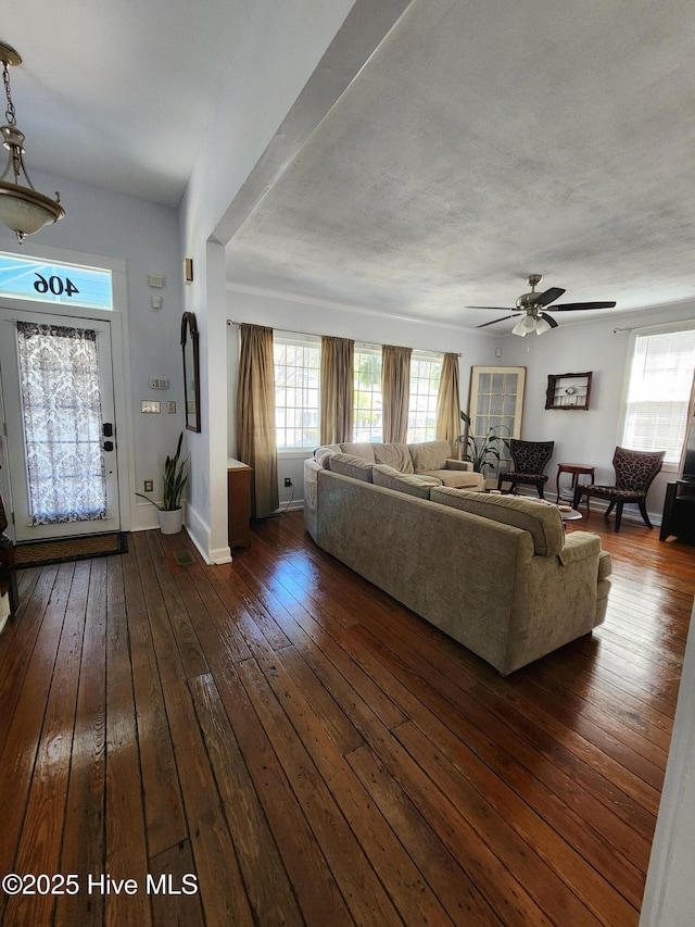unfurnished living room featuring baseboards, ceiling fan, a healthy amount of sunlight, and dark wood finished floors
