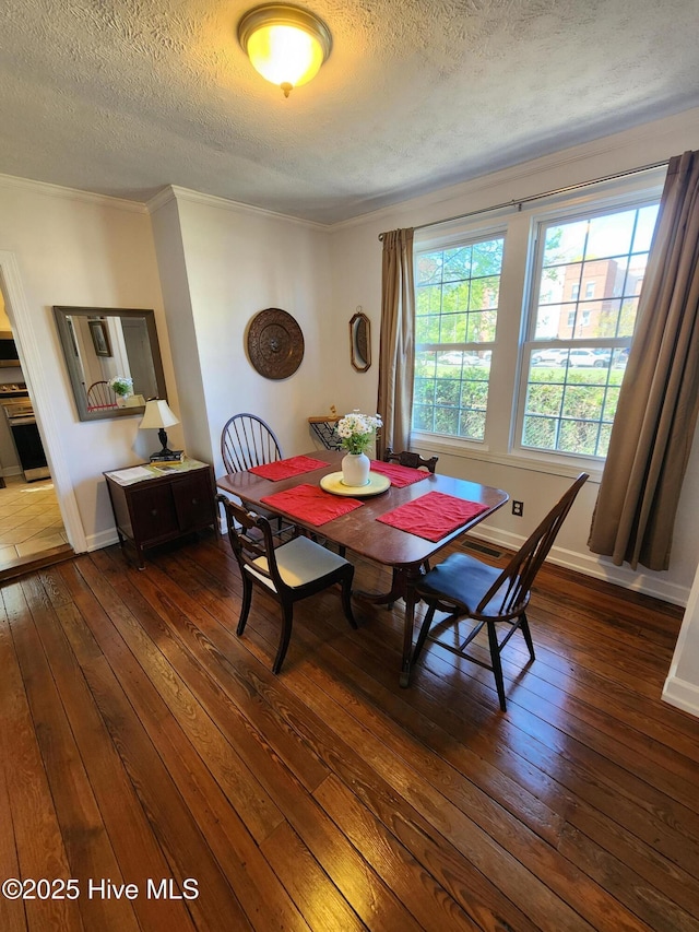 dining area with a textured ceiling, dark wood-style floors, baseboards, and crown molding