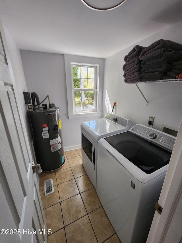 washroom featuring light tile patterned flooring, visible vents, laundry area, electric water heater, and separate washer and dryer