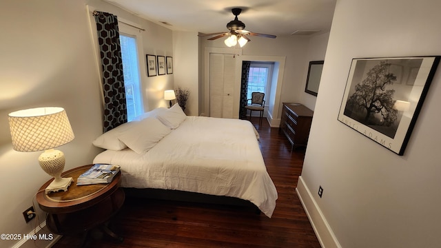 bedroom featuring a ceiling fan, visible vents, baseboards, and wood finished floors