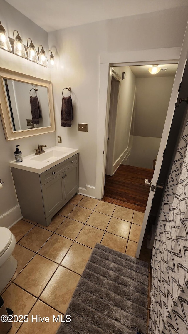 bathroom with baseboards, toilet, tile patterned floors, and vanity