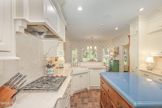kitchen with a sink, backsplash, light countertops, and brick patterned floor