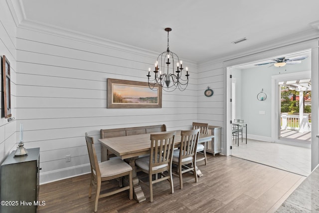 114 Sundance Cir, Hampstead, NC 28443 - dining area with crown molding, wood finished floors, a chandelier, baseboards, and wooden walls