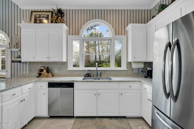 kitchen with wallpapered walls, a sink, a peninsula, and stainless steel dishwasher