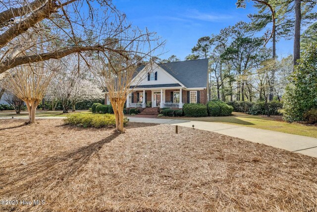 view of front of property featuring brick siding, a porch, and a front lawn