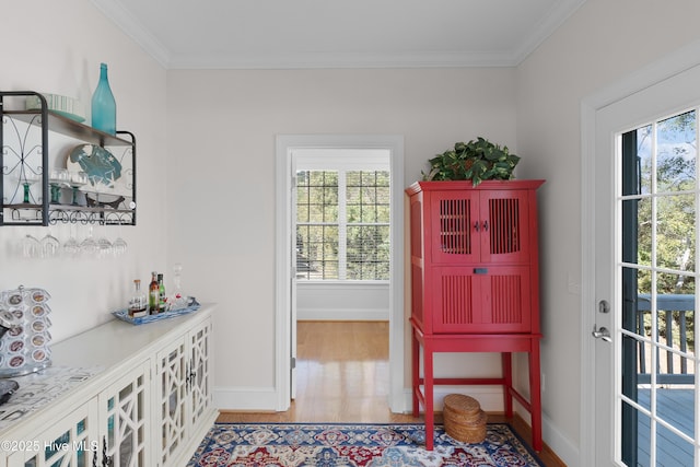 doorway to outside featuring a bar, baseboards, crown molding, and wood finished floors