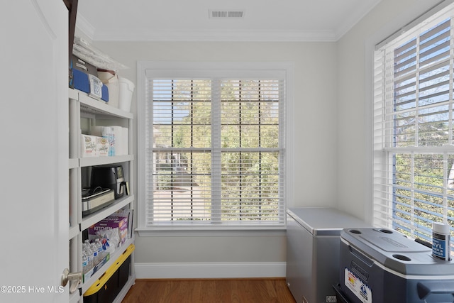 interior space featuring visible vents, crown molding, baseboards, and wood finished floors
