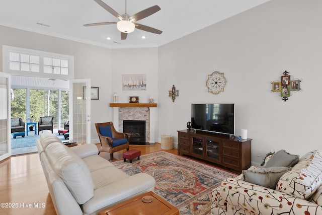 living room with crown molding, wood finished floors, ceiling fan, and a tile fireplace