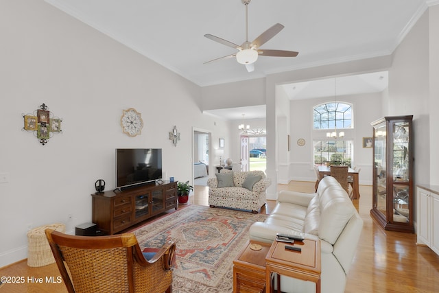 living room with ceiling fan with notable chandelier, light wood-style flooring, baseboards, and ornamental molding