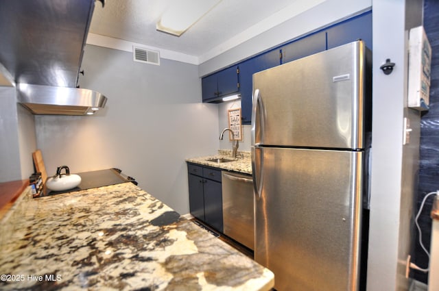 10170 Beach Dr SW Unit 305, Calabash, NC 28467 - kitchen with stainless steel appliances, a sink, blue cabinetry, wall chimney exhaust hood, and light stone countertops