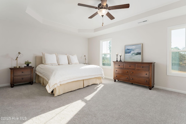 bedroom with a tray ceiling, baseboards, visible vents, and carpet floors