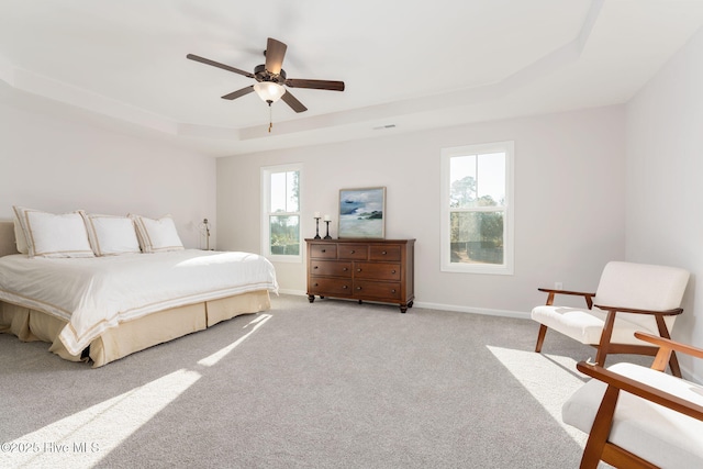 bedroom featuring a raised ceiling, light carpet, baseboards, visible vents, and ceiling fan