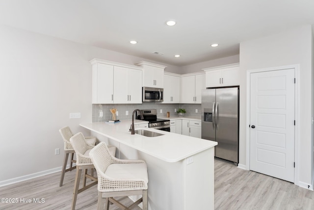 kitchen featuring light countertops, a peninsula, a sink, and stainless steel appliances