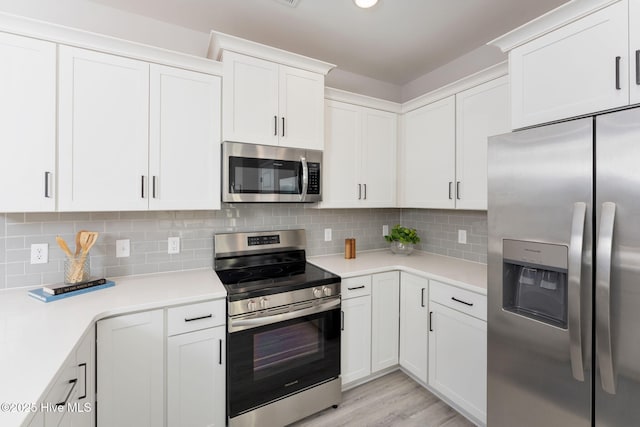 kitchen with decorative backsplash, light countertops, light wood-style flooring, white cabinets, and appliances with stainless steel finishes
