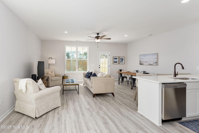 living room with baseboards, light wood-type flooring, and ceiling fan