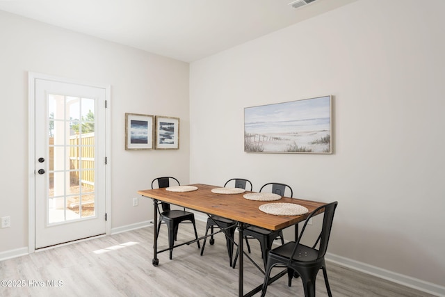 dining area with light wood-type flooring, baseboards, and a wealth of natural light