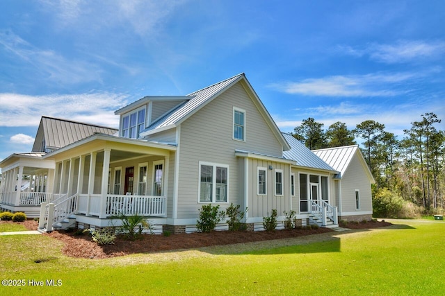 rear view of house with board and batten siding, a yard, covered porch, a standing seam roof, and metal roof