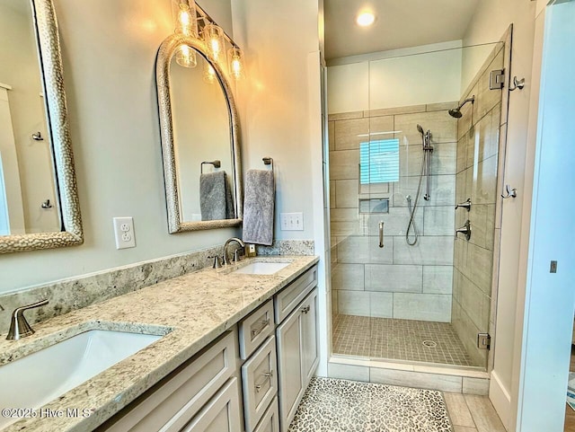 full bathroom with double vanity, tile patterned flooring, a stall shower, and a sink