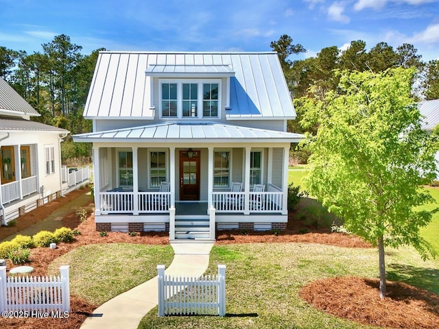 view of front of property with a porch, a standing seam roof, a front lawn, metal roof, and fence