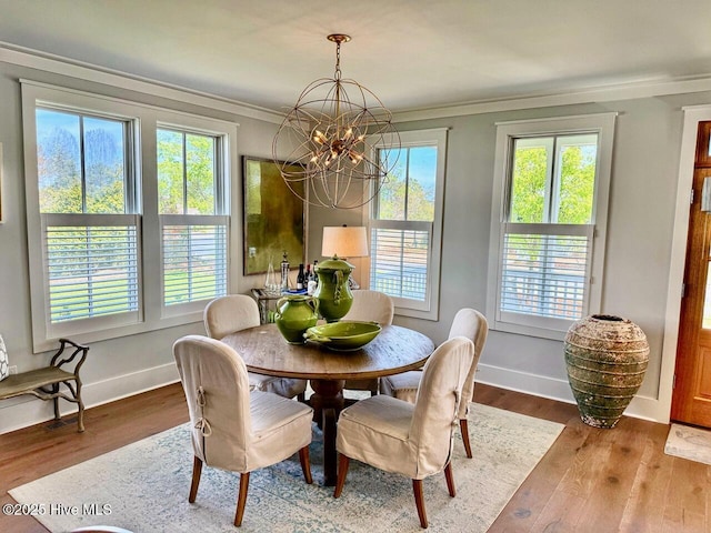 dining area featuring wood finished floors, a chandelier, ornamental molding, and baseboards