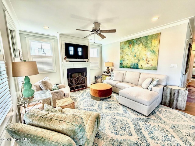 living room with a large fireplace, wood finished floors, a ceiling fan, and plenty of natural light