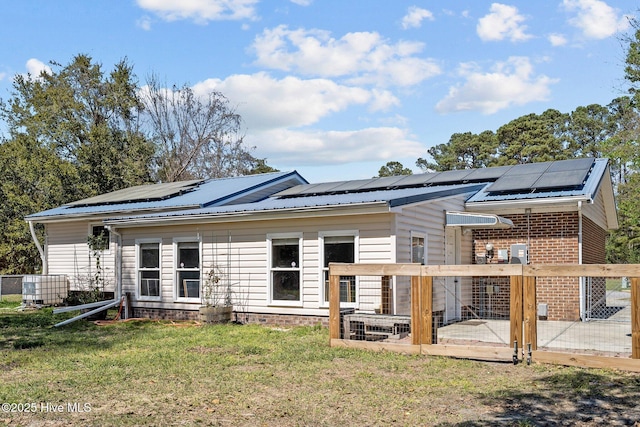 rear view of property featuring solar panels, a yard, and metal roof