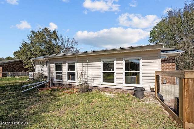 rear view of house featuring fence and a lawn