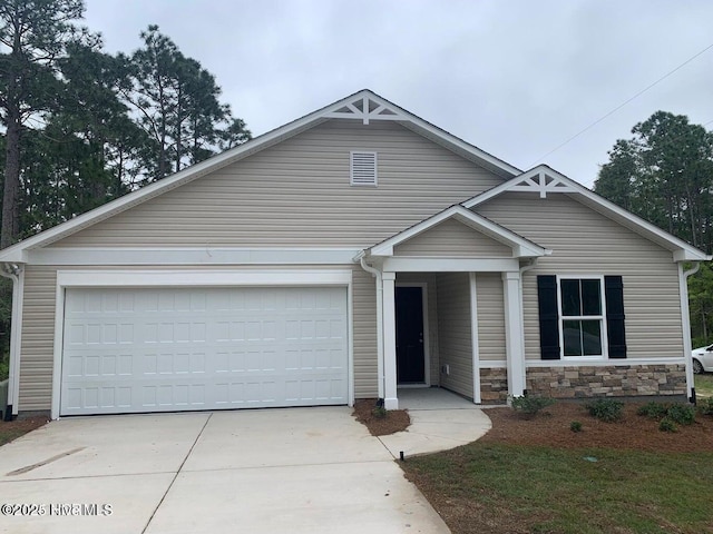 view of front of house featuring stone siding, an attached garage, and concrete driveway