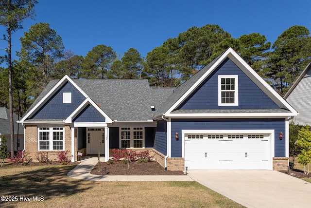 craftsman house featuring brick siding, a garage, a front lawn, and concrete driveway