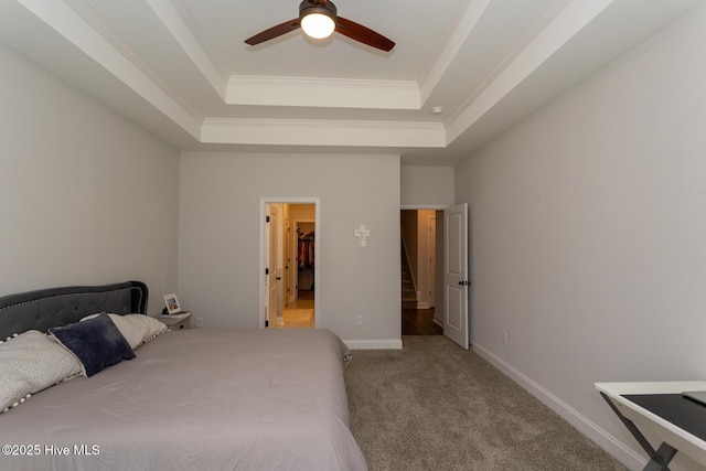 carpeted bedroom with baseboards, crown molding, and a raised ceiling