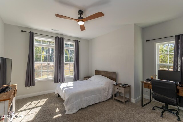 carpeted bedroom featuring baseboards, visible vents, multiple windows, and a ceiling fan