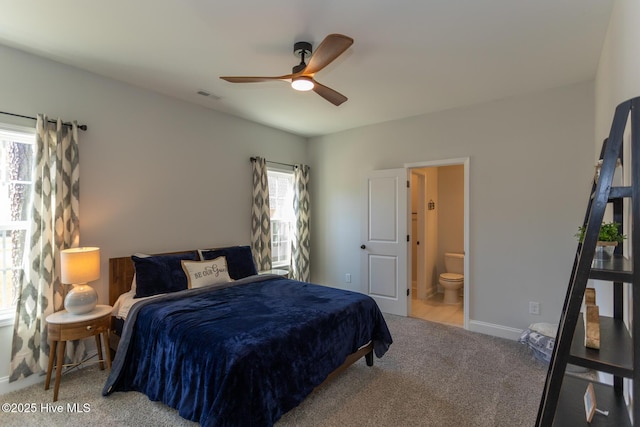 bedroom with carpet flooring, visible vents, baseboards, a ceiling fan, and ensuite bath