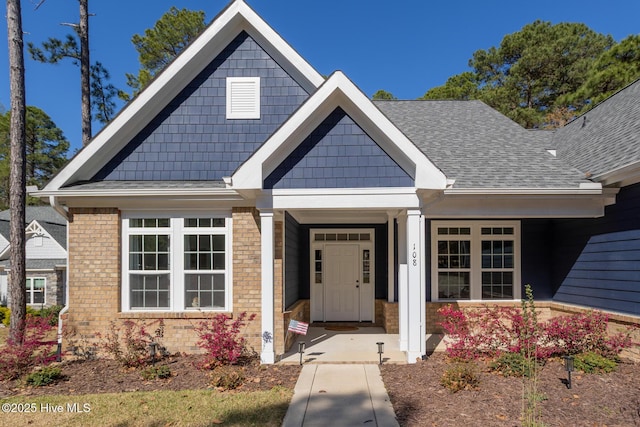 view of front of home with brick siding and roof with shingles