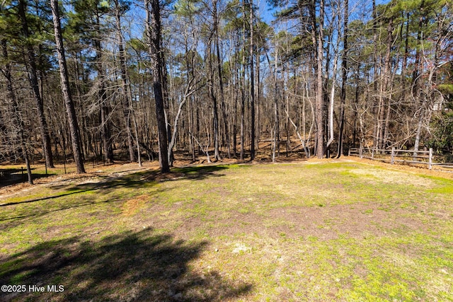 view of yard featuring a wooded view and fence