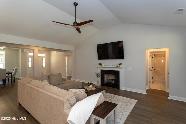 living area featuring a fireplace, dark wood-style floors, lofted ceiling, visible vents, and ceiling fan