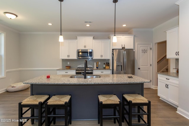 kitchen with a kitchen bar, stainless steel appliances, visible vents, white cabinets, and dark wood-type flooring