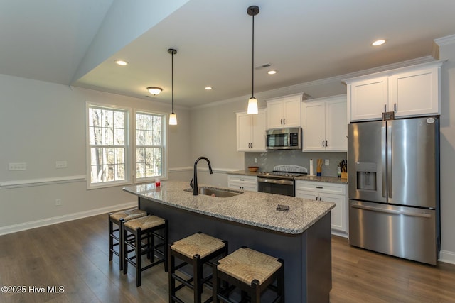 kitchen with tasteful backsplash, stainless steel appliances, dark wood finished floors, a sink, and light stone countertops