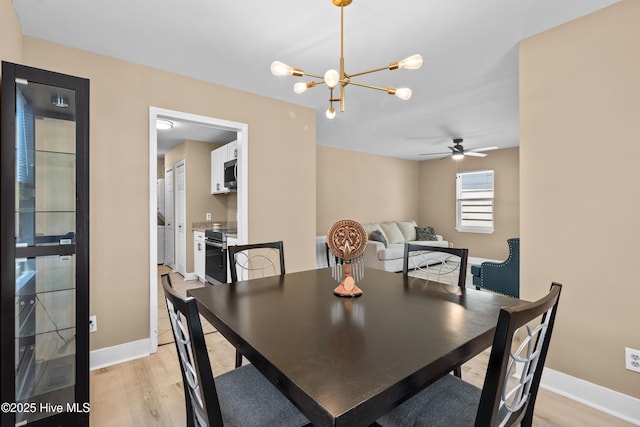 dining room with light wood-style floors, baseboards, and ceiling fan with notable chandelier