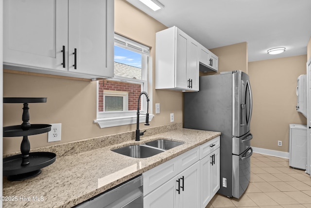 kitchen with a sink, light stone counters, white cabinets, and stainless steel appliances