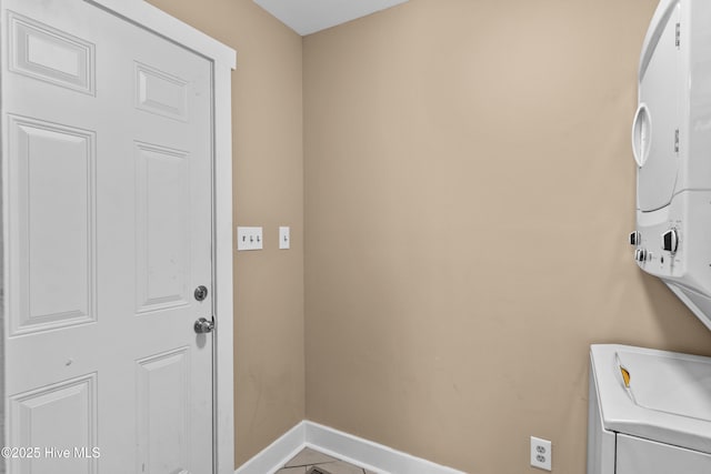 laundry room with laundry area, baseboards, and stacked washer / drying machine