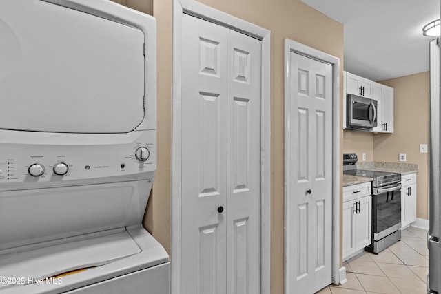 laundry area with laundry area, stacked washing maching and dryer, and light tile patterned floors