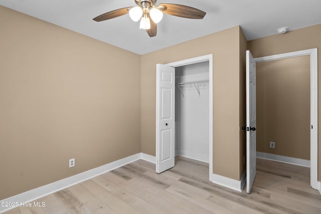 unfurnished bedroom featuring baseboards, a ceiling fan, light wood finished floors, and a closet