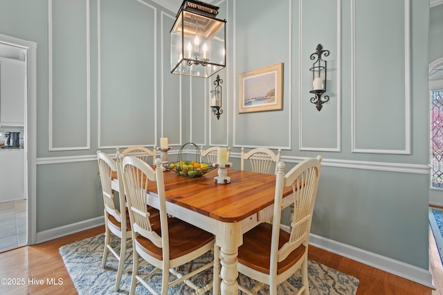 4106 Kittiwake Ct, Southport, NC 28461 - dining room featuring a chandelier, wood finished floors, a decorative wall, and baseboards
