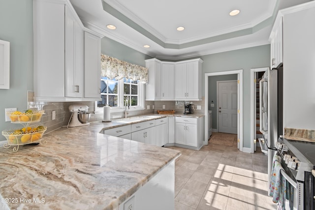 4106 Kittiwake Ct, Southport, NC 28461 - kitchen with stainless steel appliances, white cabinets, light stone countertops, crown molding, and backsplash