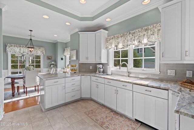 4106 Kittiwake Ct, Southport, NC 28461 - kitchen featuring plenty of natural light, a peninsula, recessed lighting, a sink, and white cabinets