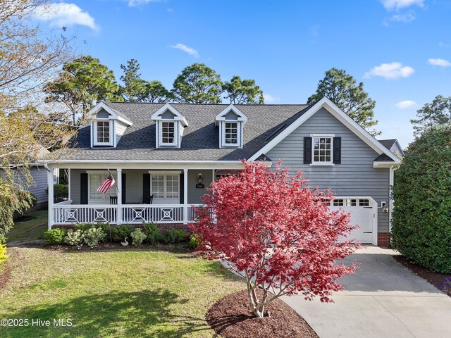 4106 Kittiwake Ct, Southport, NC 28461 - new england style home with a porch, concrete driveway, a front yard, a garage, and roof with shingles