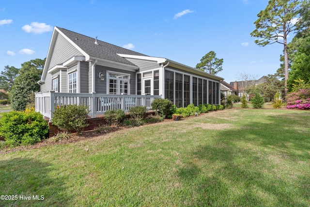 4106 Kittiwake Ct, Southport, NC 28461 - rear view of house with a yard, a sunroom, a shingled roof, and a deck