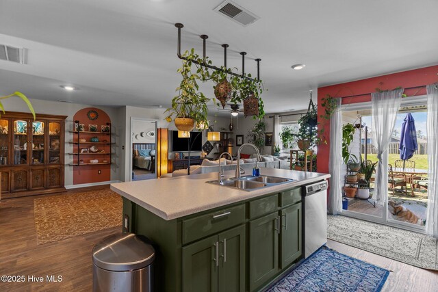 kitchen with visible vents, green cabinetry, a sink, wood finished floors, and stainless steel dishwasher