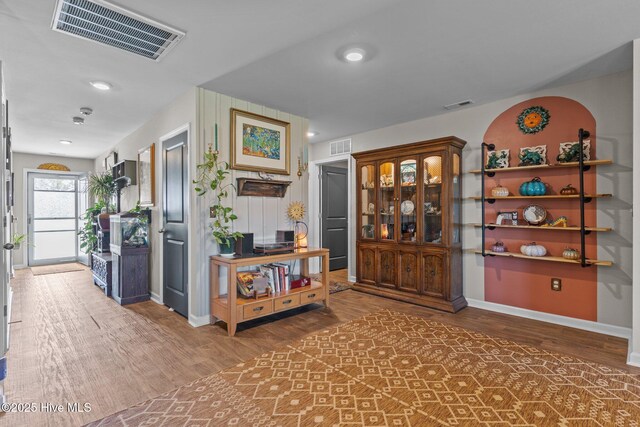 corridor with visible vents, baseboards, and wood finished floors